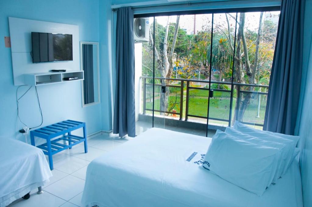 a bedroom with a bed and a large window at Hotel Serrador in Passo Fundo