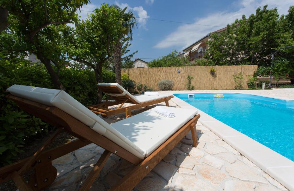 ein Paar Liegestühle neben einem Pool in der Unterkunft Villa Roso in Kaštela