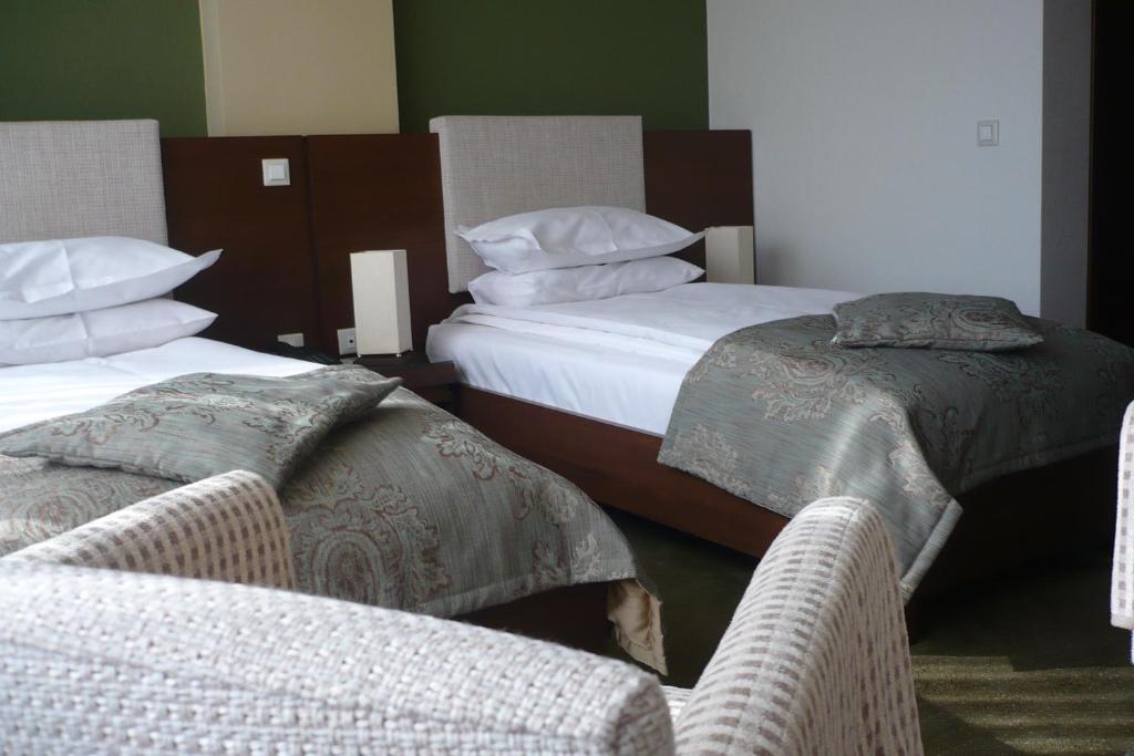 2 Betten in einem Zimmer mit 2 Stühlen und Kissen in der Unterkunft Hotel Royale in Galaţi