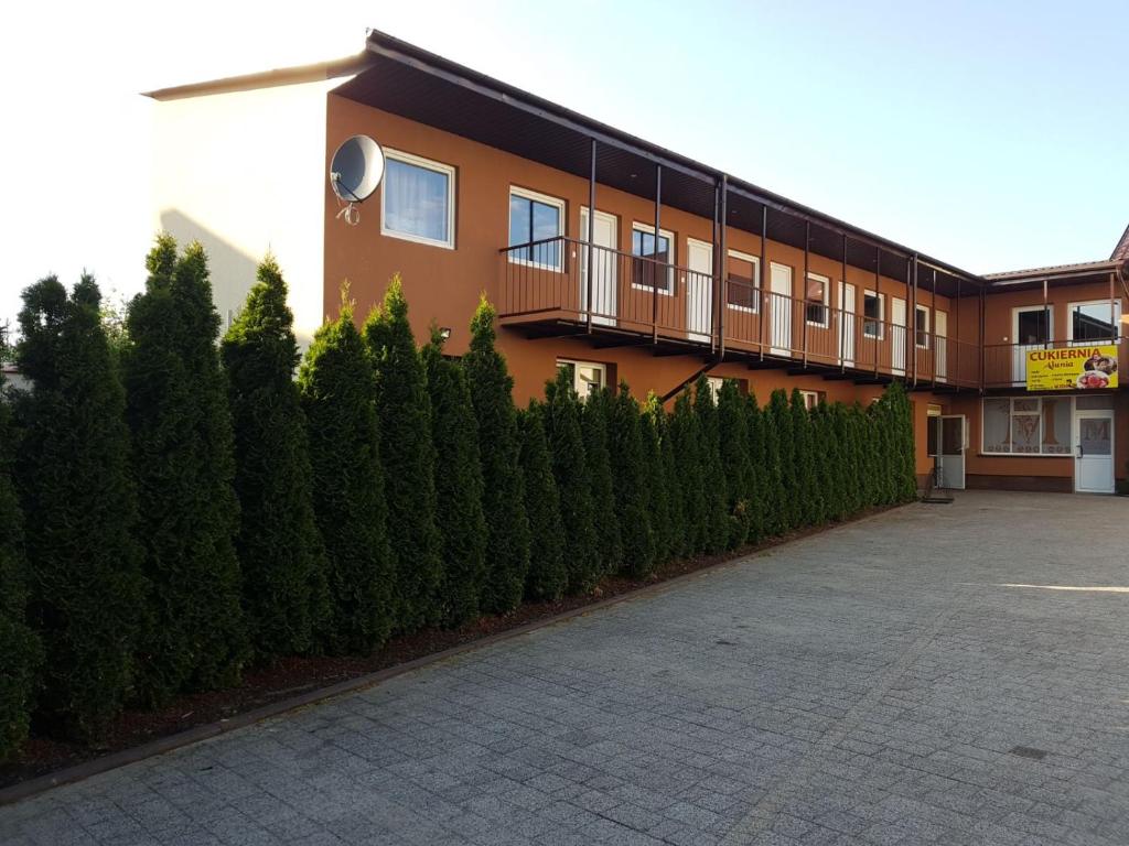 a building with a row of bushes in front of it at Motel in Myszyniec