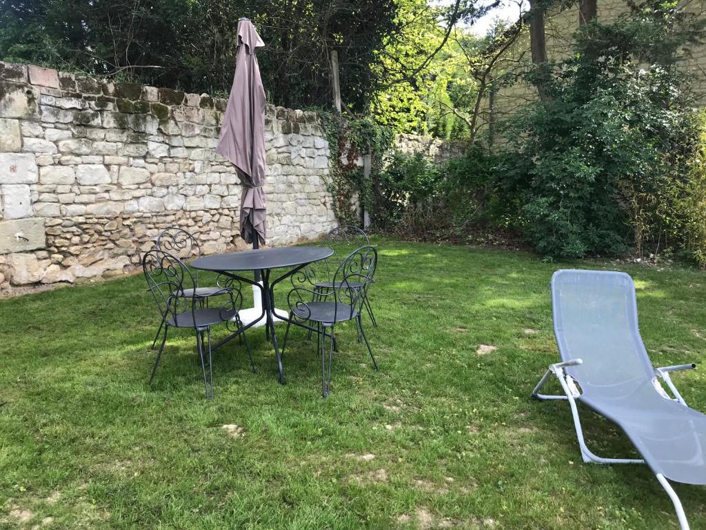 a table and chairs and an umbrella in a yard at Le petit domaine des Aubuis in Chinon