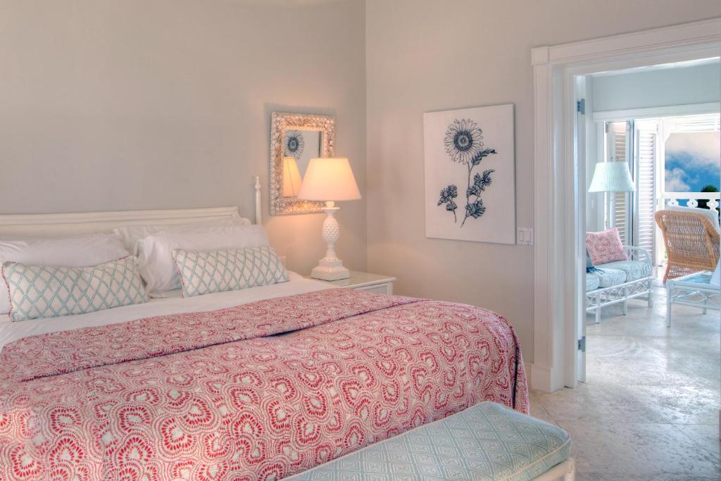 a bedroom with a bed and a chair and a window at Cobblers Cove - Barbados in Saint Peter