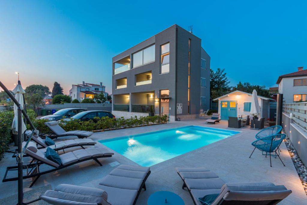 a swimming pool with lounge chairs and a house at Luxury Apartments Tramontana in Medulin