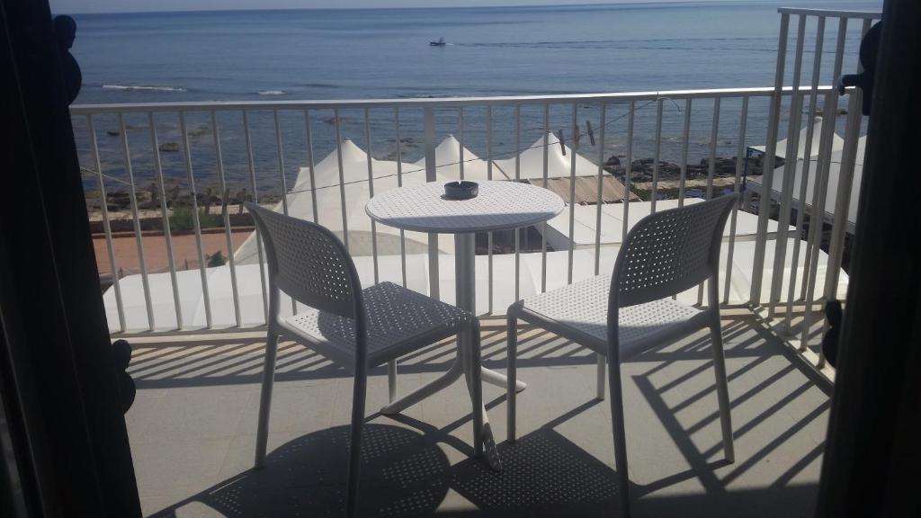 a table and chairs on a balcony with the beach at Casa Barbara in Marzamemi