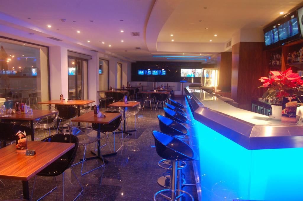 a restaurant with a swimming pool and tables and chairs at Water's Edge Hotel in Birżebbuġa