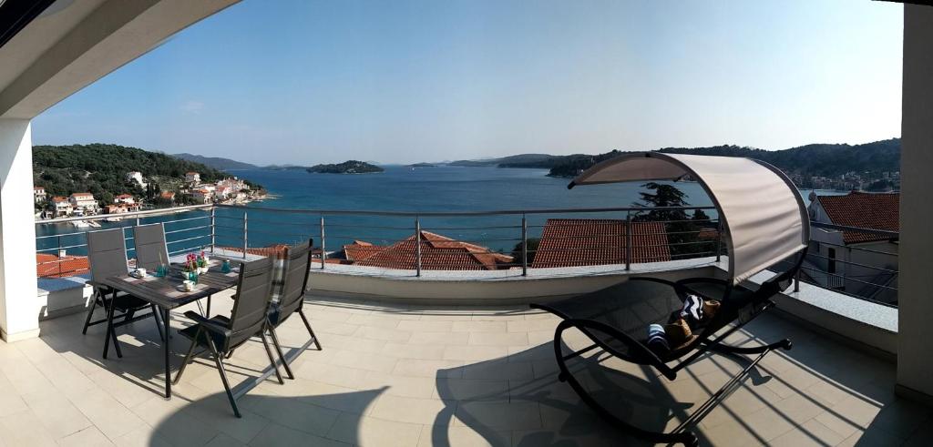 a balcony with a table and a boat on the water at Villa Big Blue, Tisno in Tisno