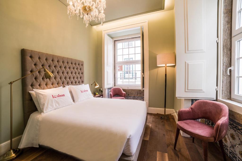 een slaapkamer met een groot wit bed en 2 stoelen bij Dare Lisbon House in Lissabon