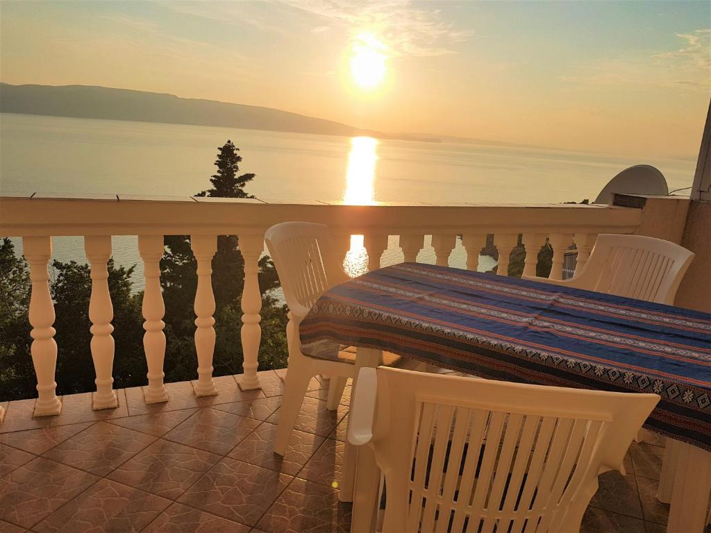 a table and chairs on a balcony with the sunset at Apartment Boras in Senj
