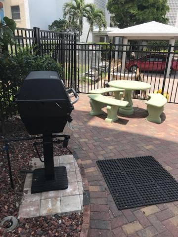 a barbecue grill and picnic tables in a yard at Crescent Arms 105N in Sarasota