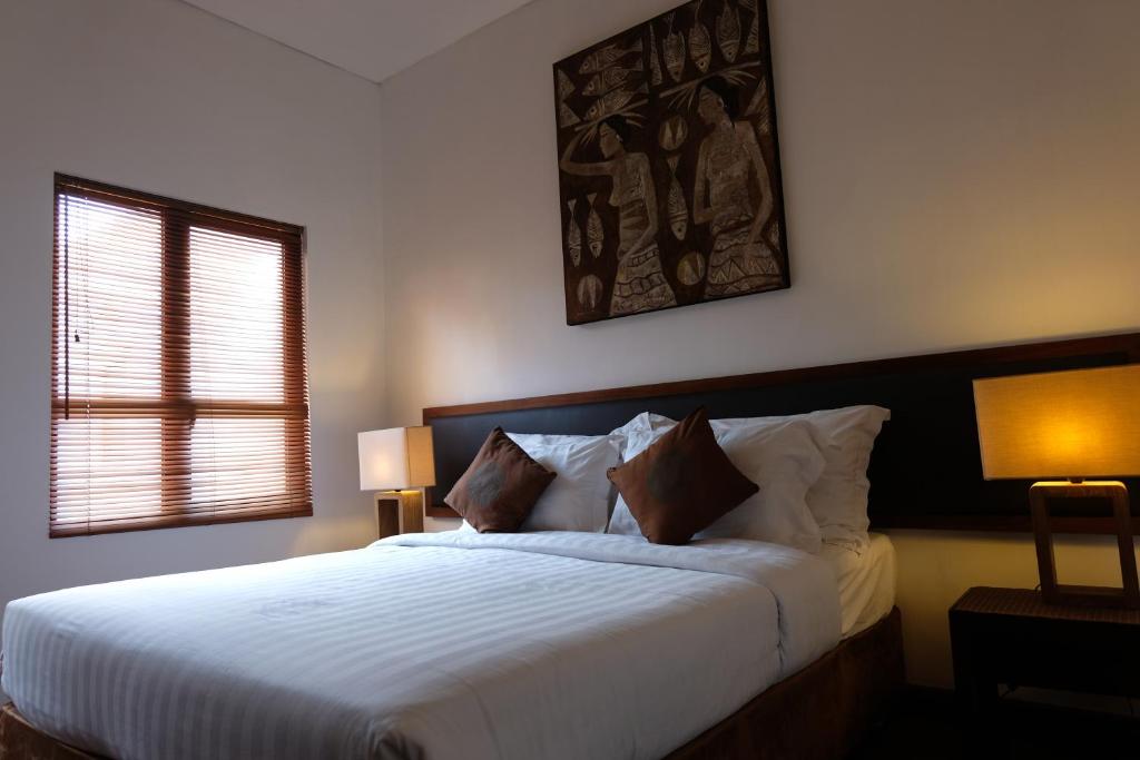 a bedroom with a large white bed with two lamps at Villa Celavi 77 in Jimbaran