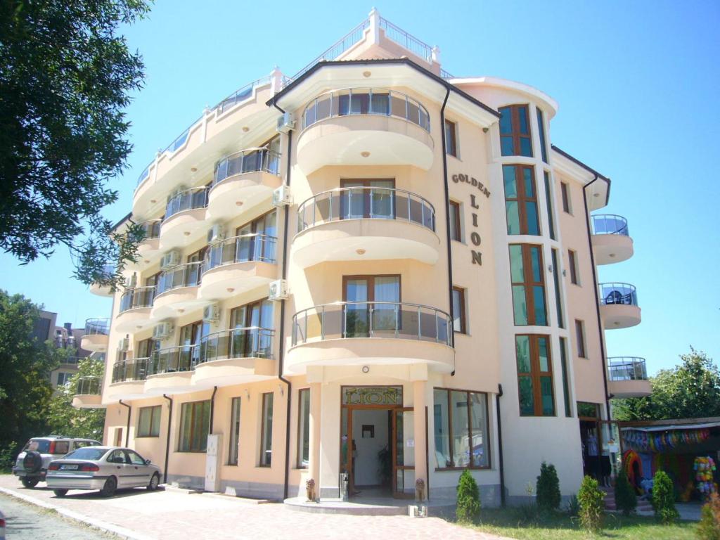 a tall white building with a car parked in front of it at Family Hotel Golden Lion in Primorsko