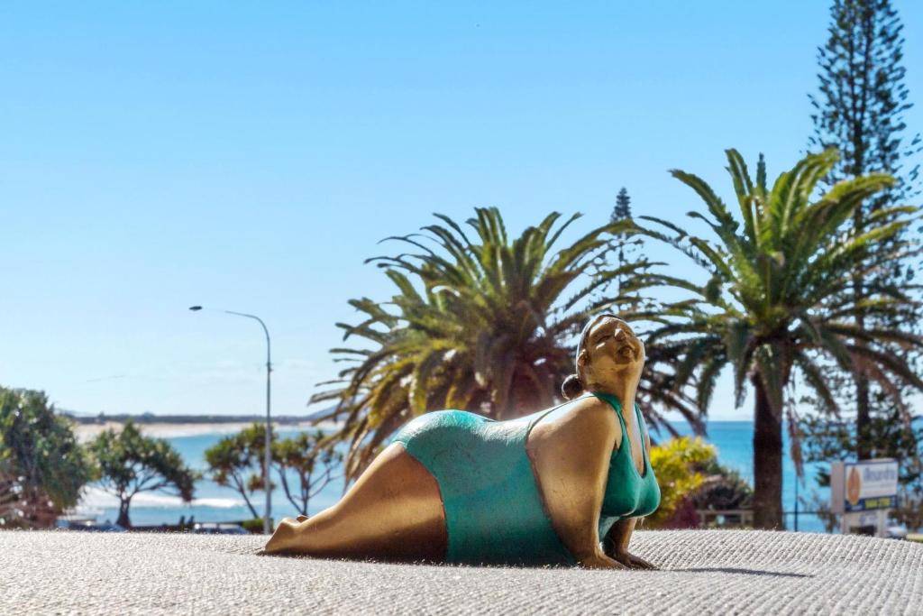 a woman laying on the beach in a bathing suit at Alex Headland Beachfront in Alexandra Headland