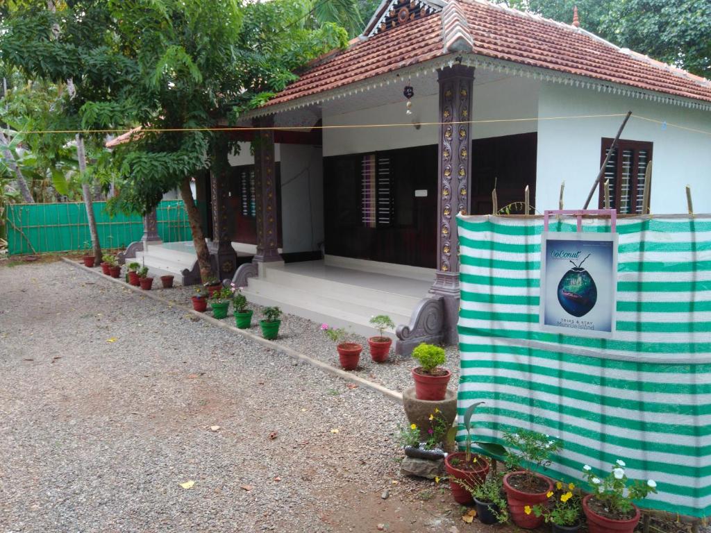 a small house with potted plants in front of it at Munroe Coconut Homestay in Munroe Island