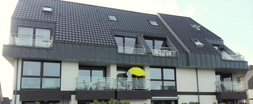 a black and white building with a balcony with a yellow umbrella at Schloss am Meer Sylt in Wenningstedt