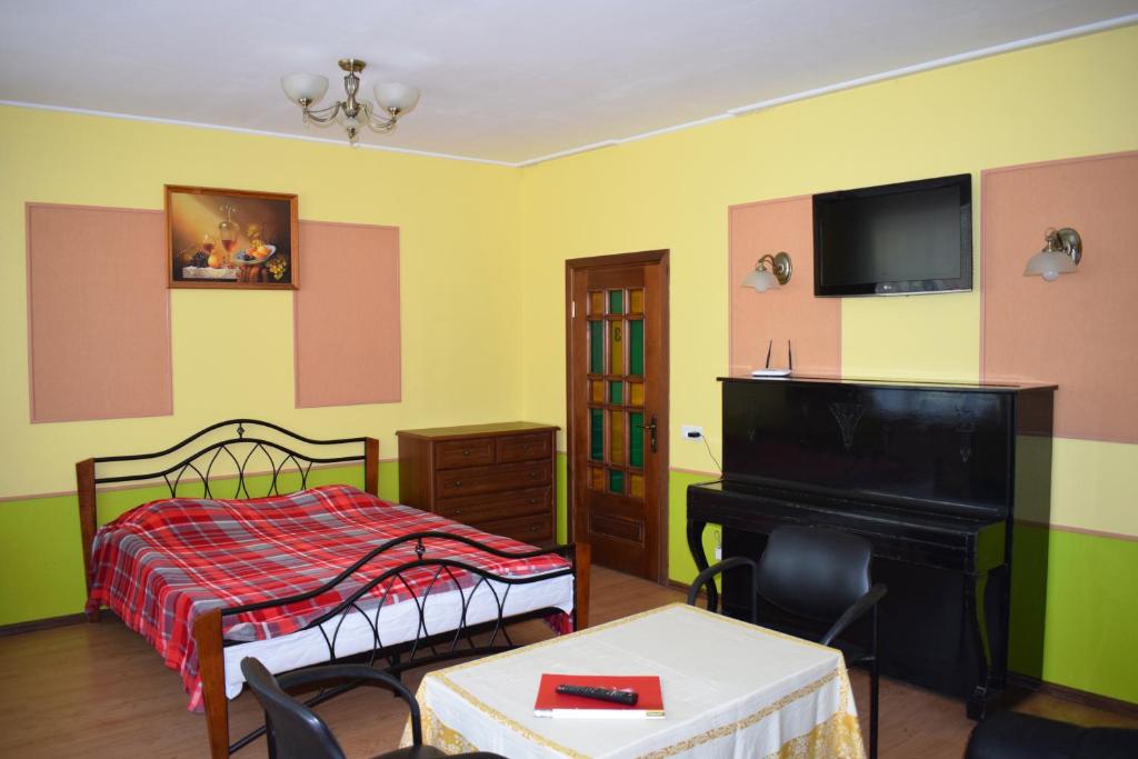 a bedroom with a bed and a table and a piano at Apartament Erfolg 12 in Daugavpils