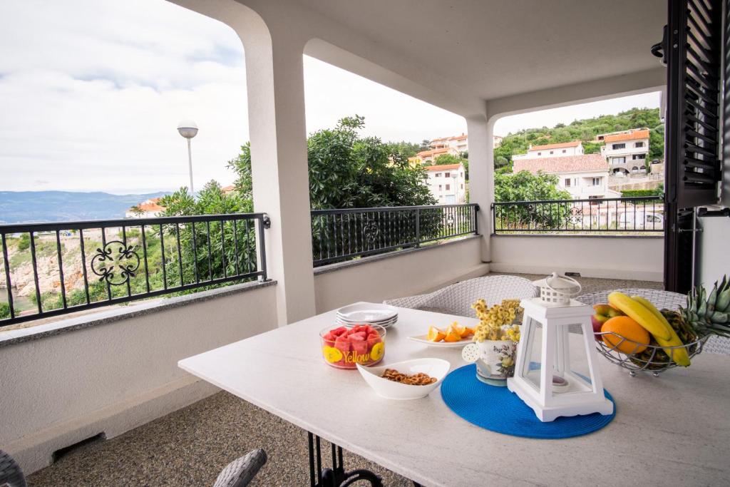 a table with fruit on a balcony with views of the ocean at Apartments Stasic in Vrbnik