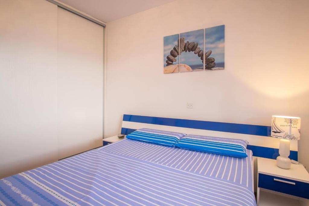 a bedroom with a bed with blue and white stripes at Apartments Stasic in Vrbnik