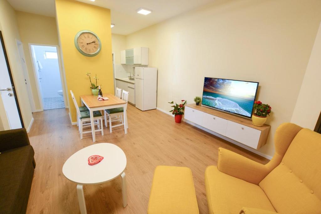 ein Wohnzimmer mit einem Sofa, einem TV und einem Tisch in der Unterkunft Rothschild Luxury Suite Haifa in Haifa