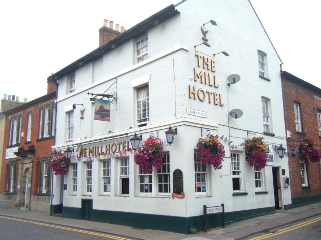 un edificio blanco con flores delante en The Mill Hotel en Bedford