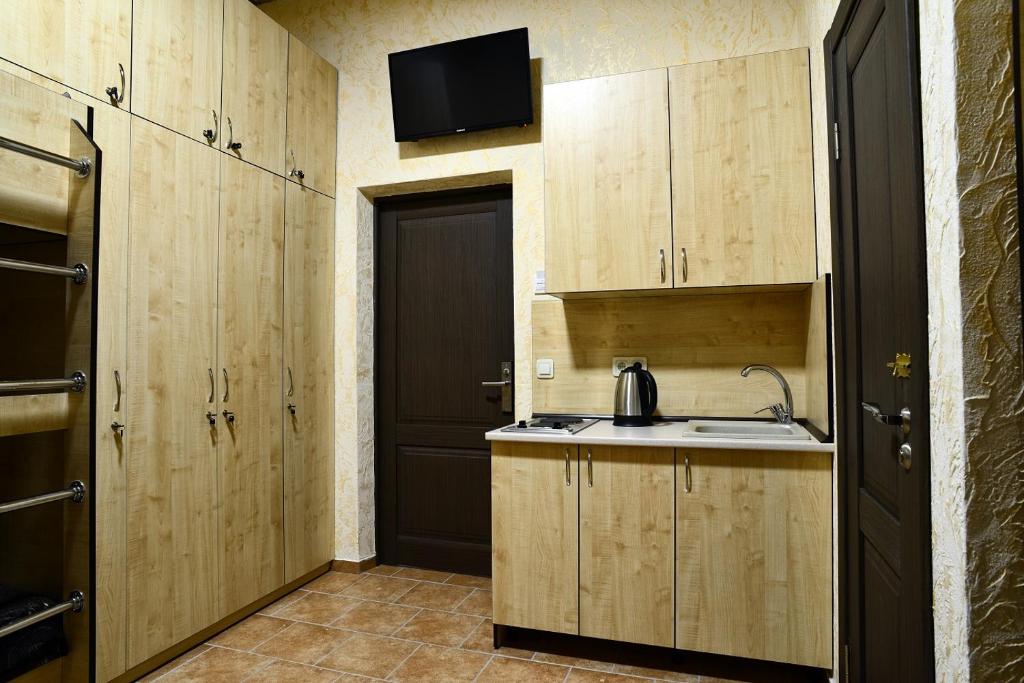 a kitchen with wooden cabinets and a sink and a door at Logovo Hostel in Odesa