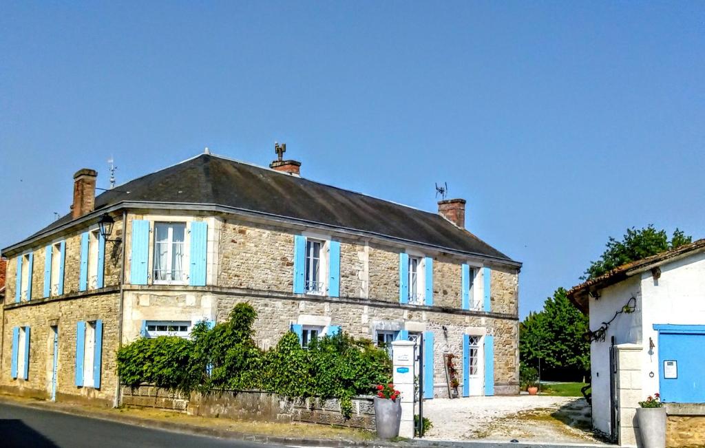 een oud bakstenen huis met blauwe ramen in een straat bij La maison de Thiré in Thiré