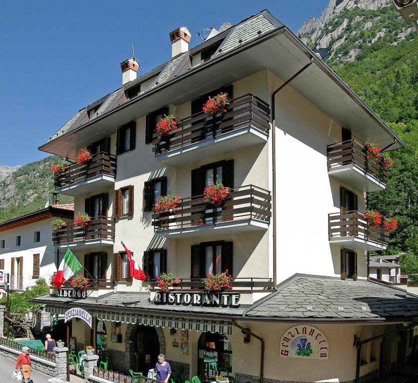 un grand bâtiment avec des boîtes de fleurs sur les balcons dans l'établissement hotel Genzianella, à Val Masino