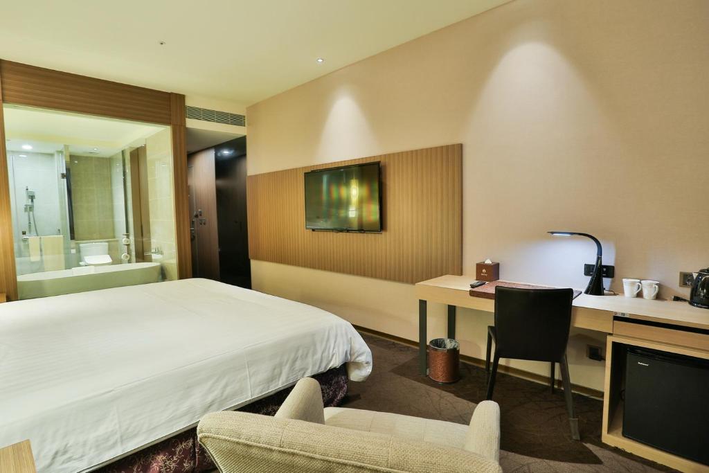 a hotel room with a bed and a desk and a television at Hotel Intrendy in Taishan