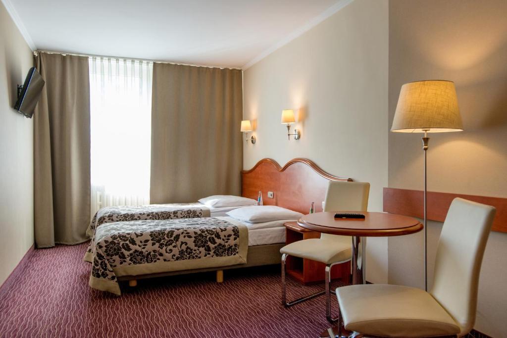克拉科夫的住宿－克拉庫斯酒店，酒店客房配有一张床铺和一张桌子。