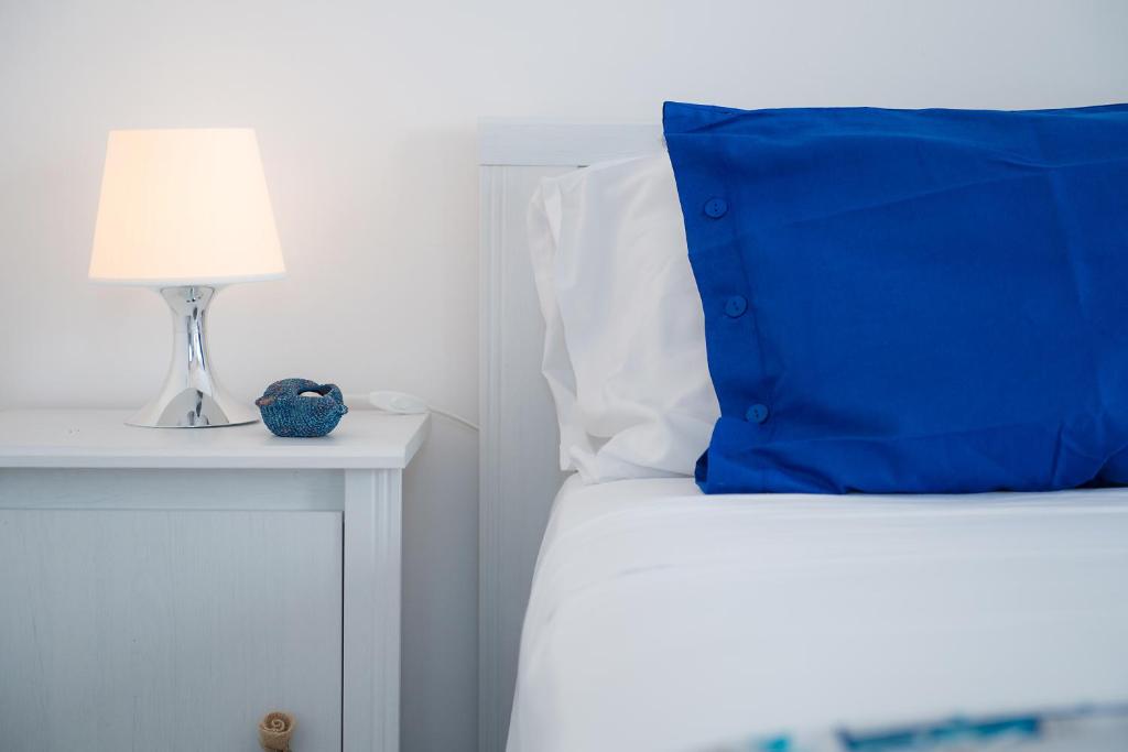 a bed with a blue pillow and a lamp on a night stand at Hotel San Giovanni in Polignano a Mare