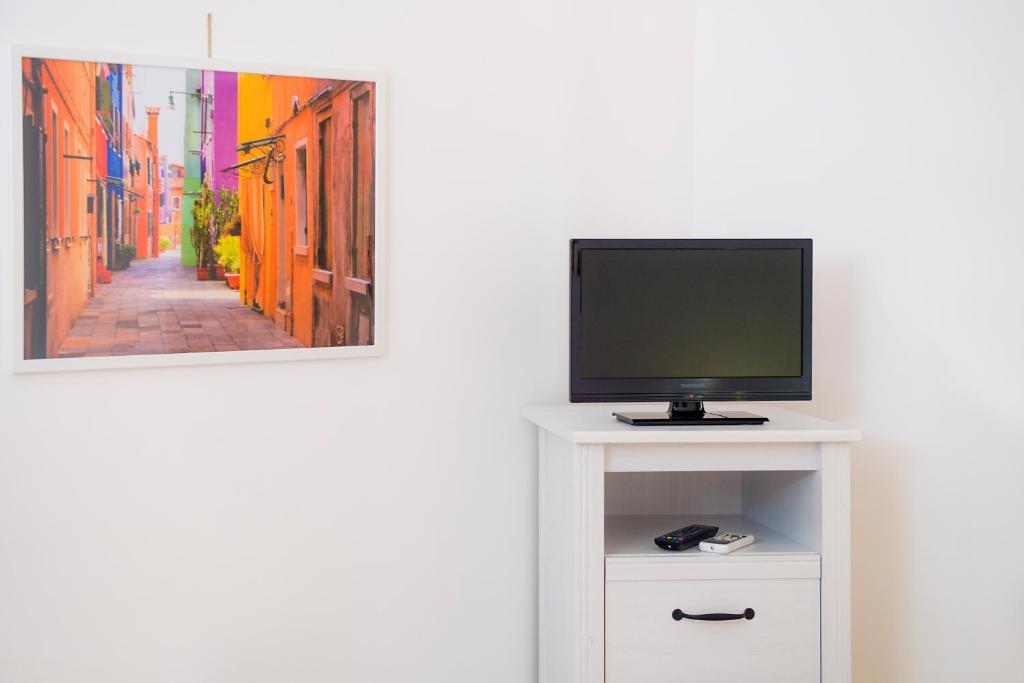 a tv on a white cabinet with a television on it at Hotel San Giovanni in Polignano a Mare
