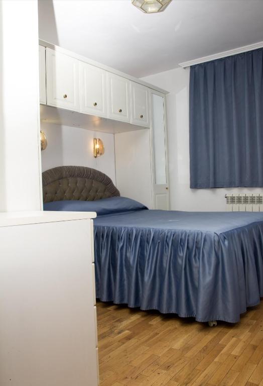 a bedroom with a bed with blue sheets and a window at Apartment Pier in Varna City