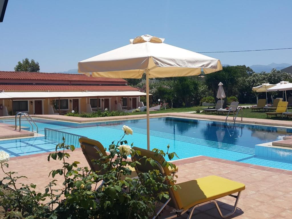 a pool with an umbrella and two chairs and a table at Androulakis Apartments in Gerani