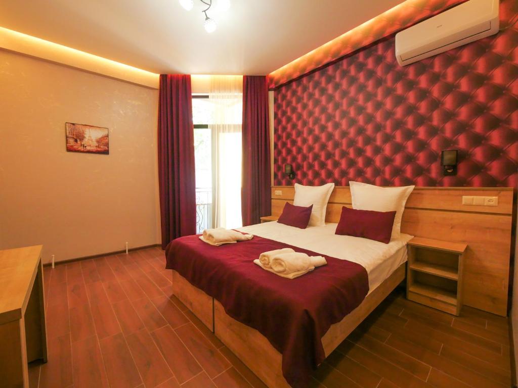 a bedroom with a bed with a red wall at La'Rooms in Kutaisi