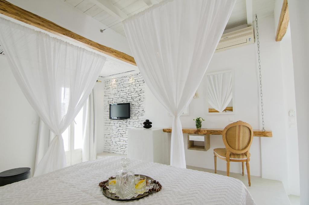 um quarto branco com uma cama com cortinas brancas em Levantes Ios Boutique Hotel em Mylopotas