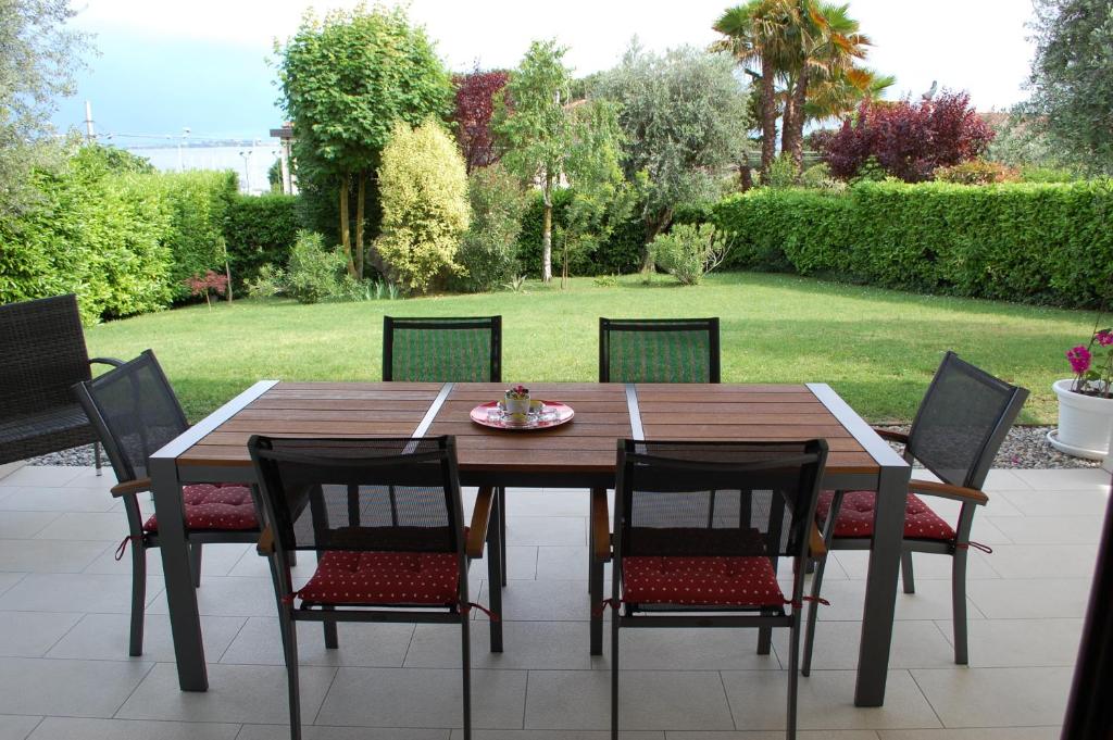 una mesa de madera y sillas con una mesa y un patio en Villa Sophora, en Moniga del Garda