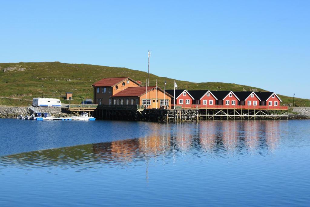 eine Gruppe roter Häuser auf einem Dock auf einem Wasserkörper in der Unterkunft Adventure Camp Mehamn in Mehamn