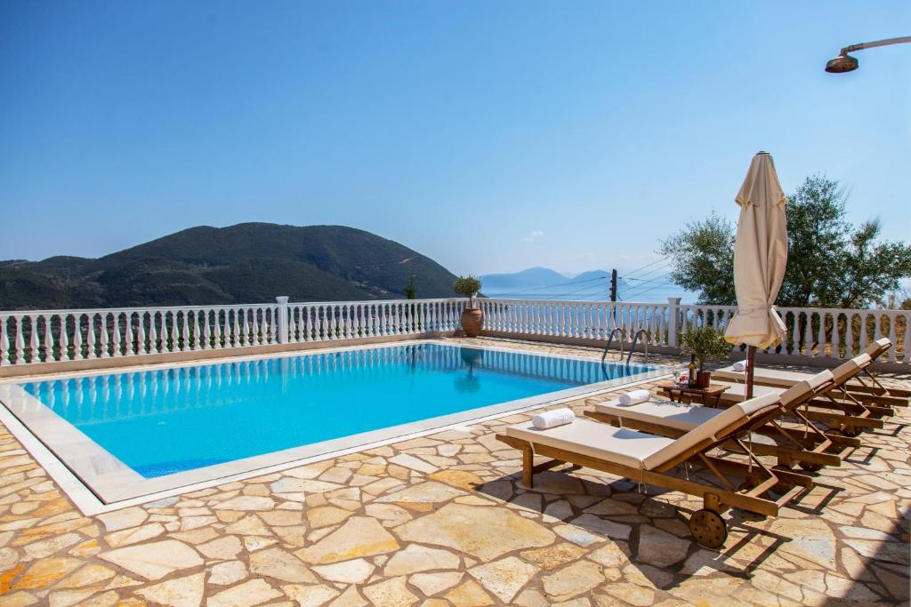 basen z 2 krzesłami i parasolem w obiekcie Villa Dream Apartments w mieście Vasiliki