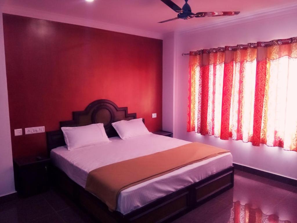 um quarto com uma cama com uma parede vermelha em Rexon Residency em Kattappana