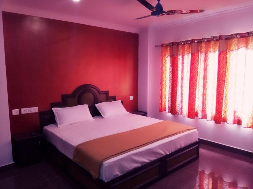 a bedroom with a bed with a red wall at Rexon Residency in Kattappana