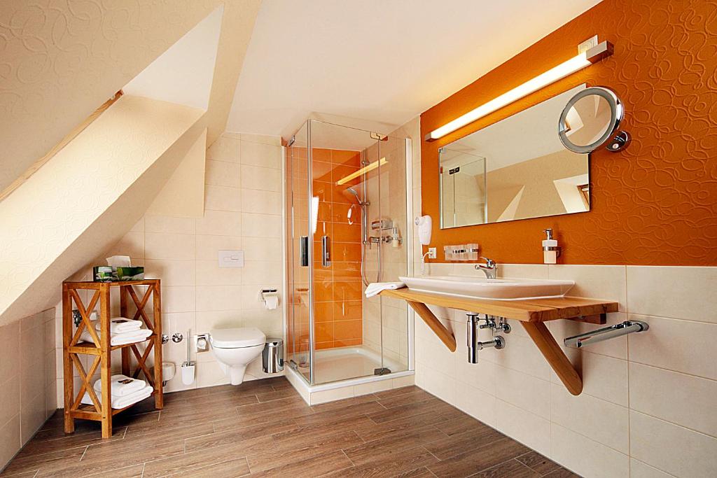 a bathroom with a sink and a shower and a toilet at Sonn'Idyll Hotel & Saunalandschaft in Rathenow