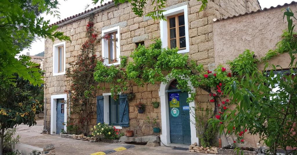 um edifício de tijolos com uma porta azul e flores em L'Orca di San Gavinu em Figari