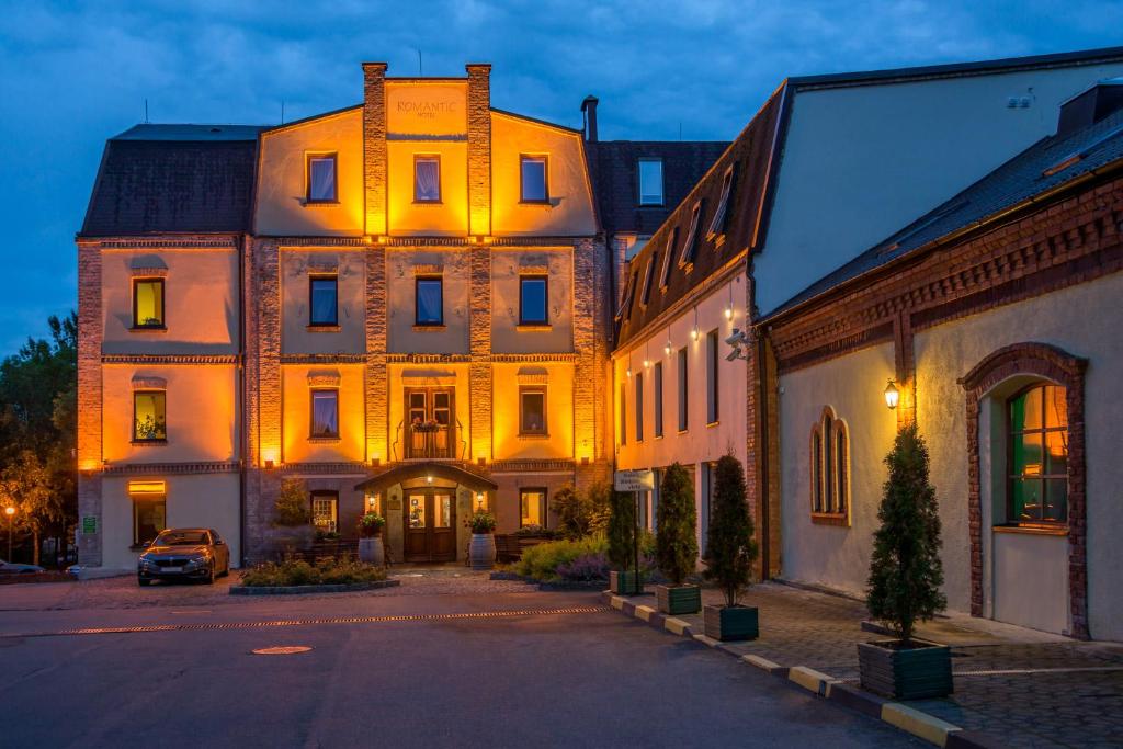 um edifício iluminado com um carro estacionado em frente em Romantic Boutique Hotel & Spa em Panevėžys