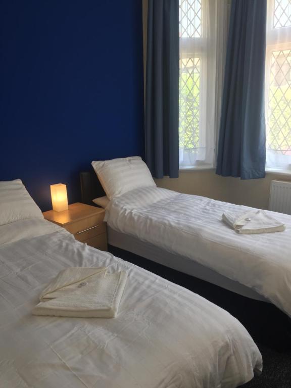 two beds in a room with blue walls and windows at Southend Central Hotel - Close to Beach, City Centre, Train Station & Southend Airport in Southend-on-Sea