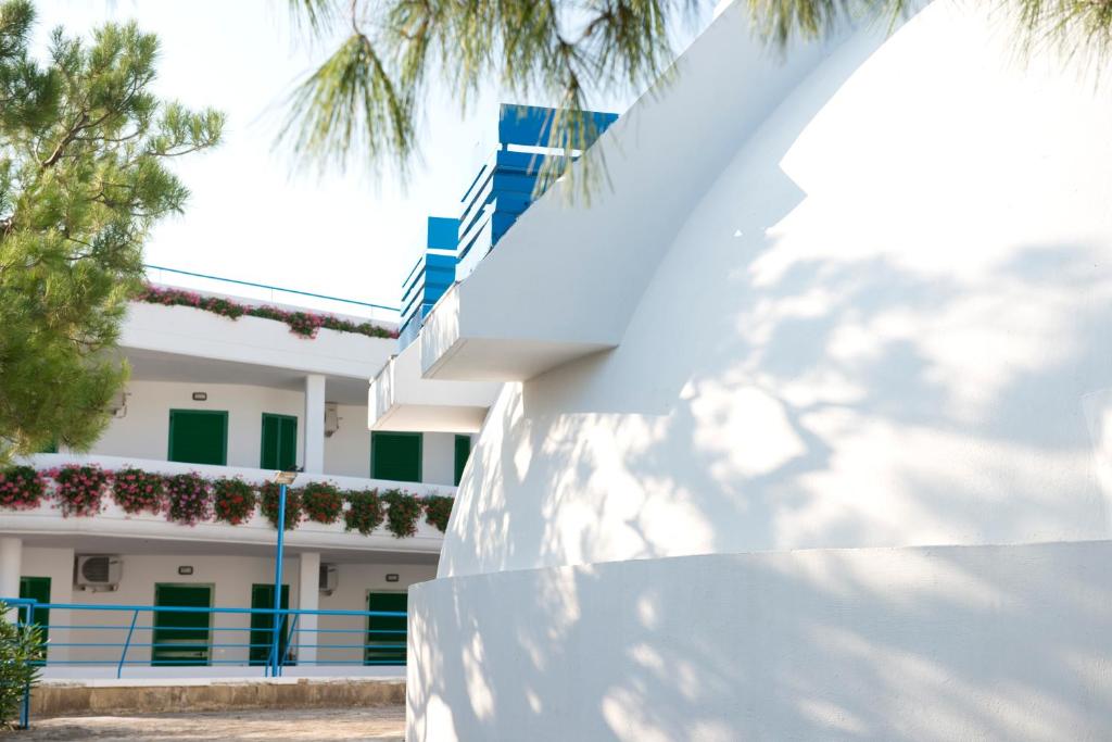 a white building with green windows and a fence at Corvino Resort in Monopoli