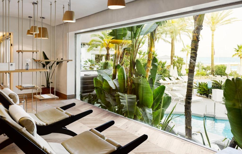 a room with chairs and a large window with a swimming pool at Puente Romano Marbella in Marbella