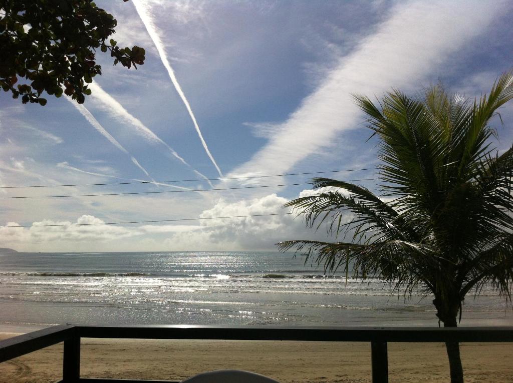 a view of a beach with a palm tree and the ocean at casa na praia in Porto Belo