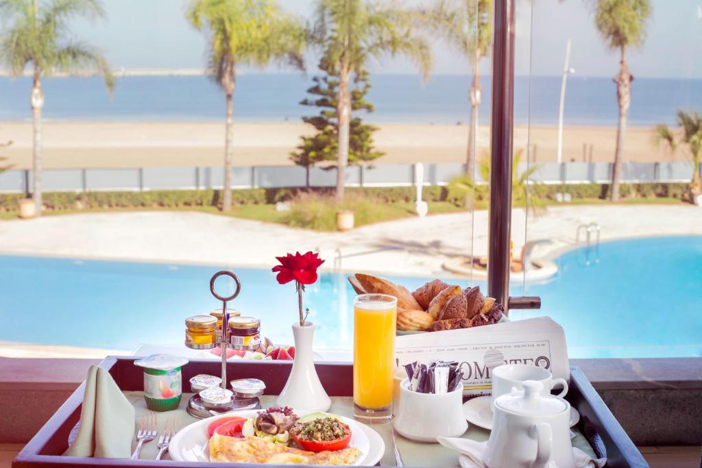 a tray of breakfast food on a table near a pool at Avanti Mohammedia Hotel in Mohammedia