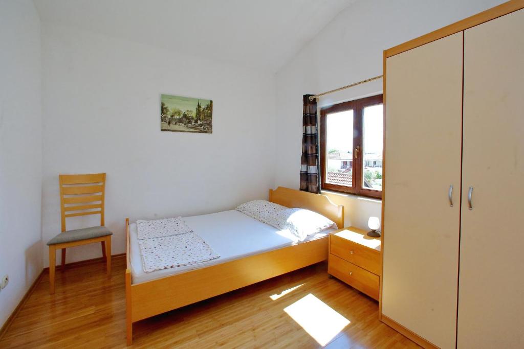 a small bedroom with a bed and a chair at Pansion Marta in Bibinje