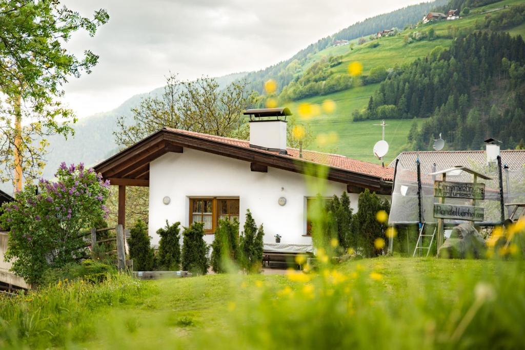 a small white house with a mountain in the background at Pardellerhof Ferienhaus in Luson