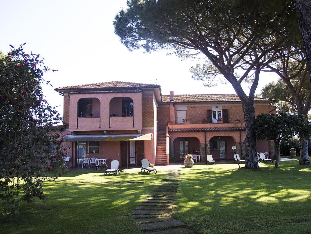 a house with chairs and a tree in the yard at Agriturismo Pavone in Castiglione della Pescaia